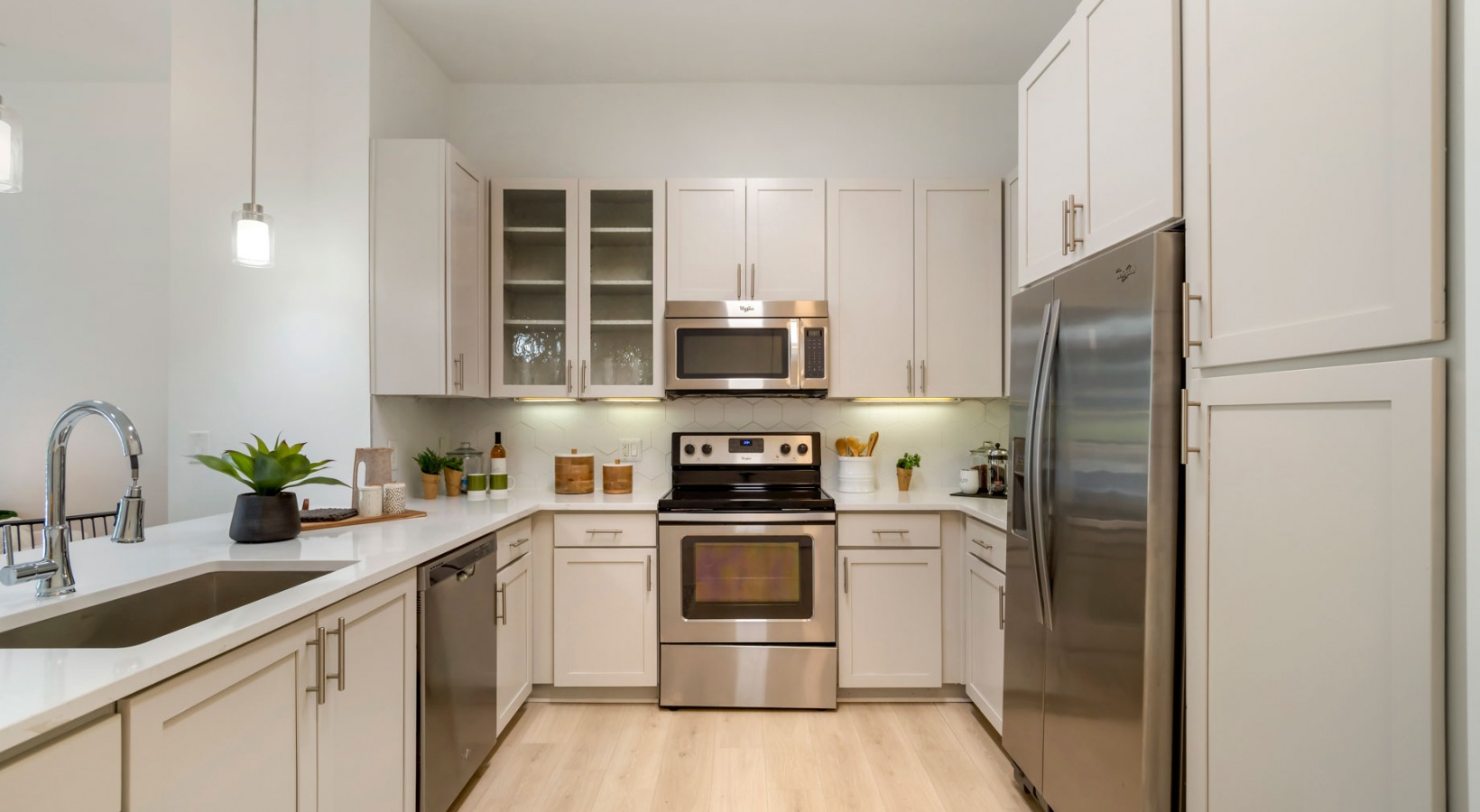 a kitchen with stainless steel appliances and white cabinets at The Allure